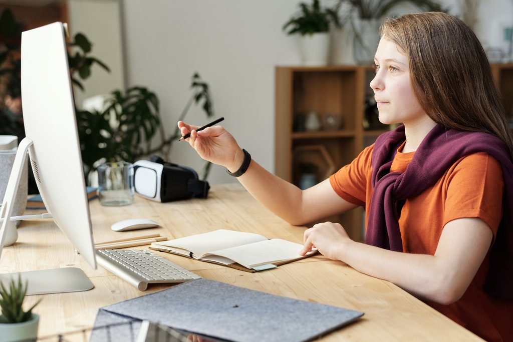 girl-holding-pencil-while-looking-at-imac-4144223